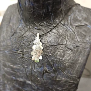 Colgante artesanal en forma de hoja de roble en plata sobre busto negro